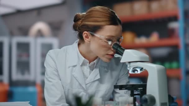 科学実験室で顕微鏡を見る成功した化学者. ハッピーな女性ラボのエキスパートの肖像画は,現代のクリニックでカメラに微笑んでいます. 医学研究に携わる美しい女性科学者. - 映像、動画