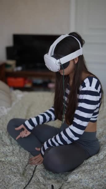 À l'aide d'un casque VR, une magnifique dame joue à un jeu vidéo dans son environnement familial. Images 4k de haute qualité - Séquence, vidéo