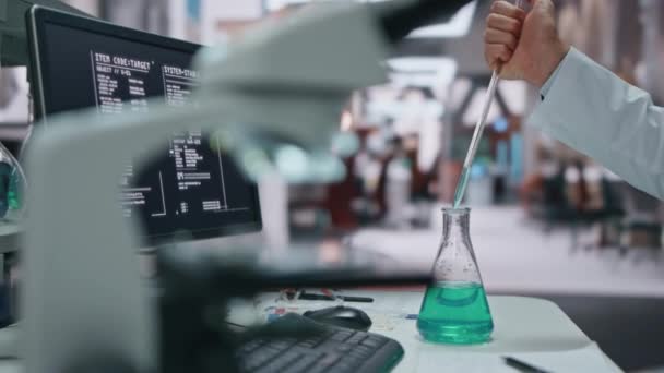 Wetenschapper hand vullen pipet uit glazen fles maken experiment in laboratorium close-up. Serieuze lab technicus in badjas zet drugsmonster onder microscoop. Biotechnoloog die geneesmiddelen onderzoekt - Video