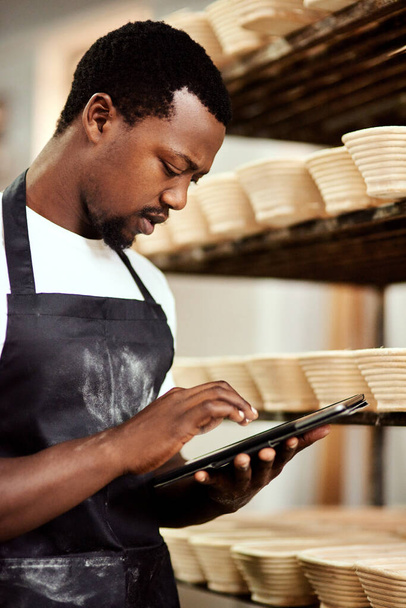 La fraîcheur est ma promesse à tous mes clients. un homme utilisant une tablette numérique pendant qu'il travaillait dans une boulangerie - Photo, image