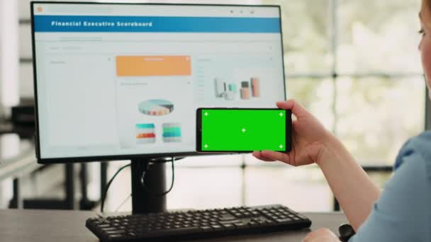 Zakenvrouw analyseren smartphone app met greenscreen template in startup coworking ruimte. Persoon op zoek naar geïsoleerde chromakey display met mockup op digitaal mobiel apparaat, copyspace. - Video