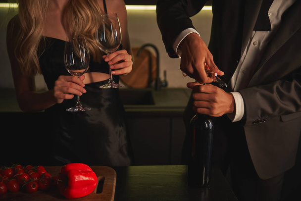 abgeschnittene Ansicht eines jungen multikulturellen Paares, das sich darauf vorbereitet, zu Hause Gourmet-Rotwein zu trinken - Foto, Bild