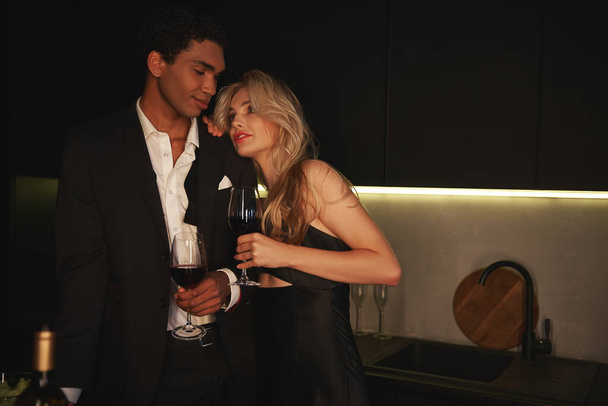 amorevole giovane coppia multirazziale trascorrere del tempo insieme in serata con il vino rosso in bicchieri - Foto, immagini