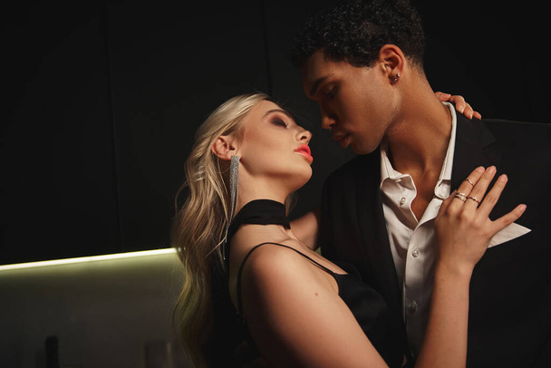 attrayant couple multiracial avec accessoires posant ensemble et se préparant à embrasser avec amour - Photo, image