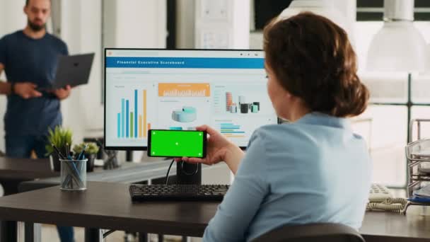 Офісний працівник дивиться на зелений колір на дисплеї смартфона, аналізуючи ізольоване компонування хромосоми на мобільному пристрої на роботі. Жінка тримає телефон, який показує порожній макет. - Кадри, відео