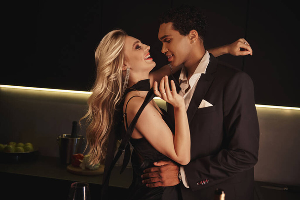fröhlich gutaussehender afrikanisch-amerikanischer Mann umarmt seine schöne, fröhliche Freundin und schaut sie an - Foto, Bild