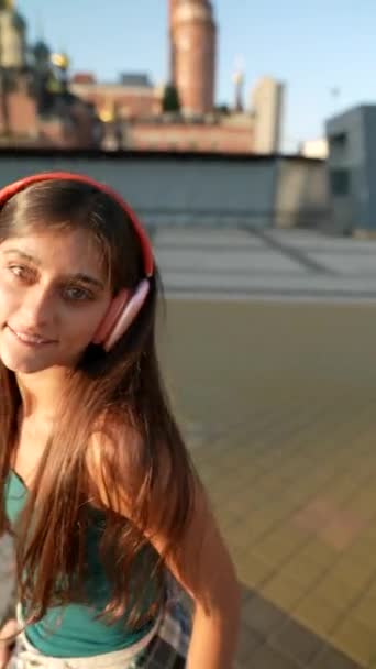 Het stadsplein komt tot leven als een pittige jonge vrouw danst met een koptelefoon. Hoge kwaliteit 4k beeldmateriaal - Video