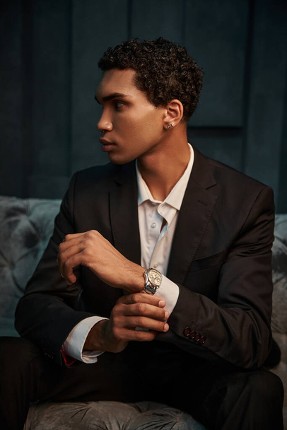appealing young african american male model in chic suit with accessories posing and looking away - Photo, Image