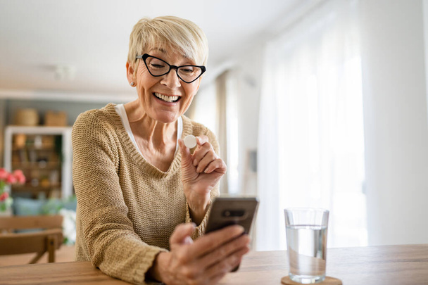 Jedna starší běloška stará žena brát léky léky nebo doplněk vitamin šumivé tablety se sklenicí vody doma mít videohovor on-line konzultace skuteční lidé zdravotní péče koncept - Fotografie, Obrázek