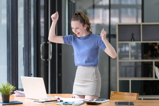 Glückliche Geschäftsfrau lacht vor Freude über die guten Nachrichten über die Arbeit am Arbeitsplatz, schaut freudig auf den Laptop-Bildschirm und ist aufgeregt. Das lässige und erfolgreiche Konzept von Business - Foto, Bild