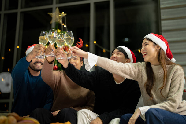 Işıklı şampanya bardaklarını kapatın. Asyalı arkadaş, kadın ve erkek kutluyor. Mutlu arkadaşlar Noel arifesinde yemek ve şampanyayla kutlanır.. - Fotoğraf, Görsel