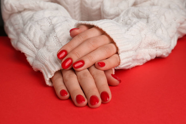 Woman with gel polish on nails at red table, closeup - Foto, Imagem