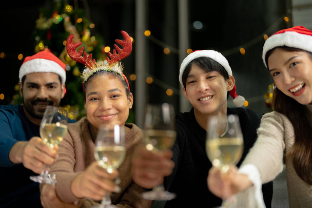 Işıklı şampanya bardaklarını kapatın. Asyalı arkadaş, kadın ve erkek kutluyor. Mutlu arkadaşlar Noel arifesinde yemek ve şampanyayla kutlanır.. - Fotoğraf, Görsel