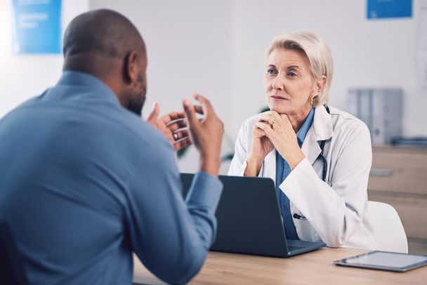 Woman, doctor and listening to man in consultation for healthcare advice at clinic. Mature medical professional consulting with patient for support, wellness services and communication in hospital. - Photo, Image