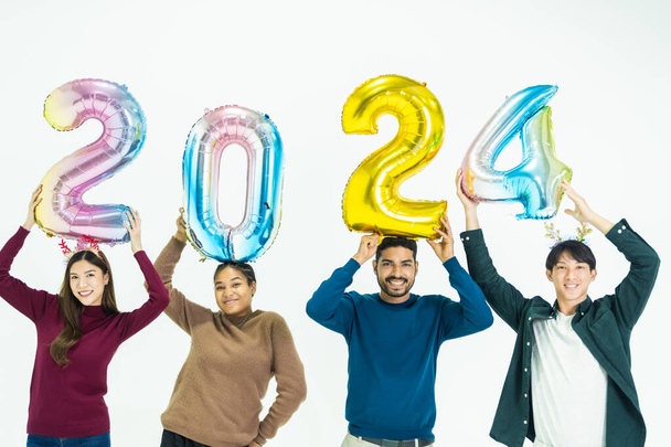 grupo de personas que sostienen globos de colores de fantasía burbuja del número 2024 para el nuevo año. hombres y mujeres de pie sobre un fondo blanco. celebración de la fiesta feliz año nuevo - Foto, imagen