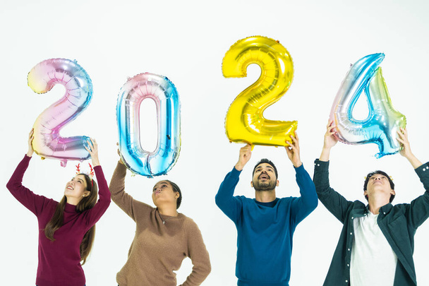 skupina lidí, kteří drží fantasy barevné balónky bublina čísla 2024 na nový rok. muži a ženy stojící na bílém pozadí. oslava šťastného nového roku Party - Fotografie, Obrázek
