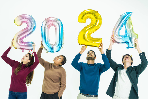 grupo de personas que sostienen globos de colores de fantasía burbuja del número 2024 para el nuevo año. hombres y mujeres de pie sobre un fondo blanco. celebración de la fiesta feliz año nuevo - Foto, Imagen