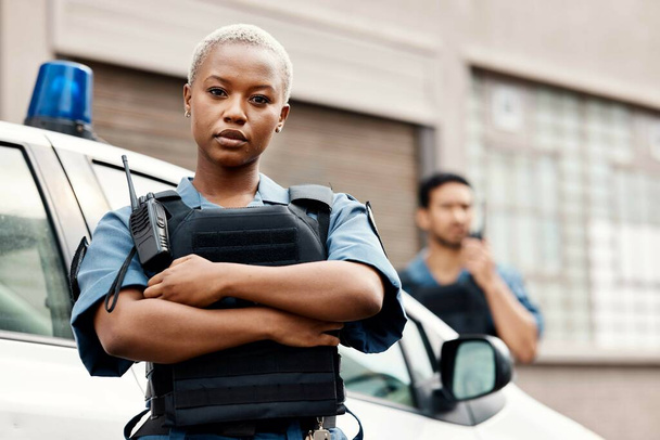 Black woman, police and arms crossed in city for law enforcement protection or street safety. Portrait of serious African female person, security guard or cop ready for justice or crime in urban town. - Photo, Image