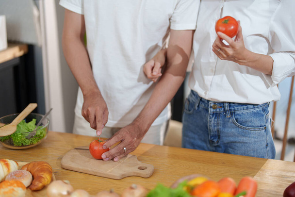 Ev mutfağında yemek veya salata yapmak için domates kesen bir çift.. - Fotoğraf, Görsel
