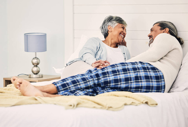 Szerelem, pihenés és egy idős pár az ágyban együtt, kötődés reggel, miközben élvezi a nyugdíjas otthon. Boldog, beszélgetés és egy idős nő a férjével a hálószobában, míg a nyaralás. - Fotó, kép