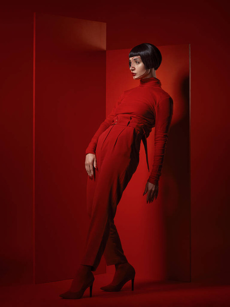 Fashion, posing and a woman on a red background, thinking with a vision for style and aesthetic. Serious, idea and a retro model or girl in stylish clothes or a suit isolated on a studio backdrop. - Foto, Imagem