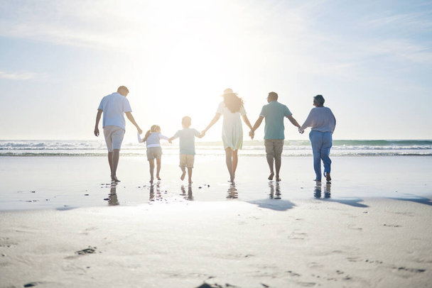 Beach, holding hands and grandparents, parents and kids for bonding, quality time and relax in nature. Family, travel and back of mom, dad and children walking on holiday, vacation and adventure. - Photo, Image