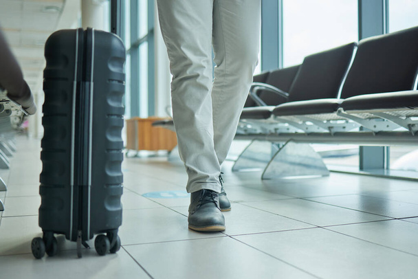 Travel, suitcase and person legs walking to flight, international opportunity and global journey in lobby. Luggage, entrepreneur or business man at airport for vacation, travel agency or hospitality. - Photo, Image