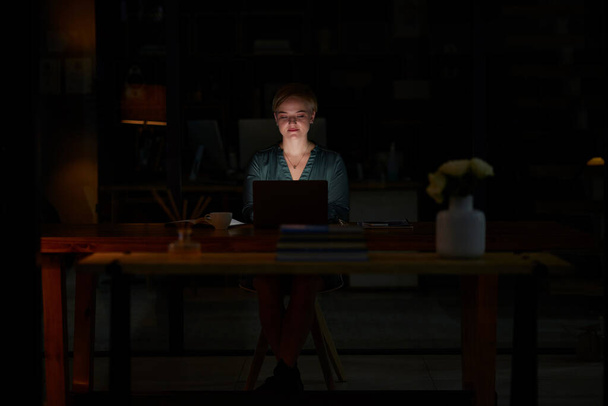 Night, laptop and serious with woman in office for planning, overtime and corporate mockup. Deadline, technology and email with employee typing proposal at desk for business, trading and internet. - Photo, Image