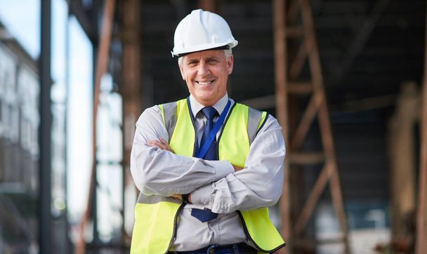Construction site, engineer and portrait of senior man outdoor for building project management. Happy contractor person with arms crossed for civil engineering, safety and development or innovation. - Photo, Image