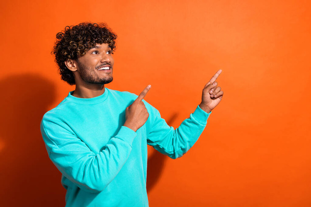 Photo of nice positive guy toothy smile look indicate fingers empty space ad isolated on orange color background. - Photo, Image