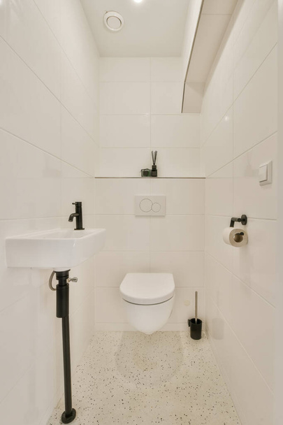 egy fehér fürdőszoba fekete-fehér csempével a padlón, WC az előtérben - kép felülről - Fotó, kép