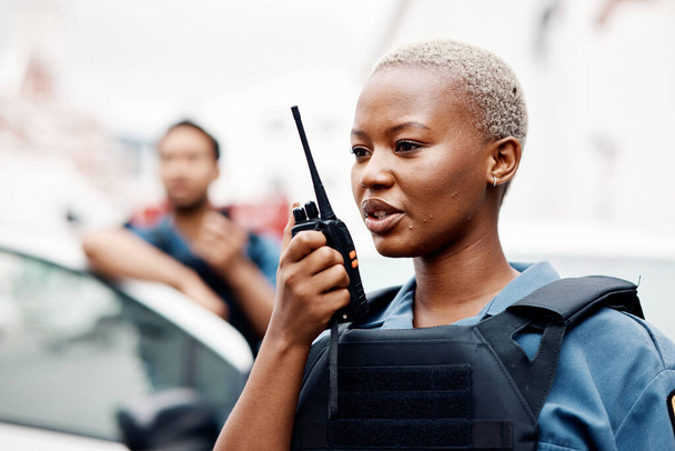 Black woman, police and walkie talkie for radio in city communication, reinforcement or emergency. African female person, security guard or cop calling backup for crime on patrol in urban town street. - Photo, Image