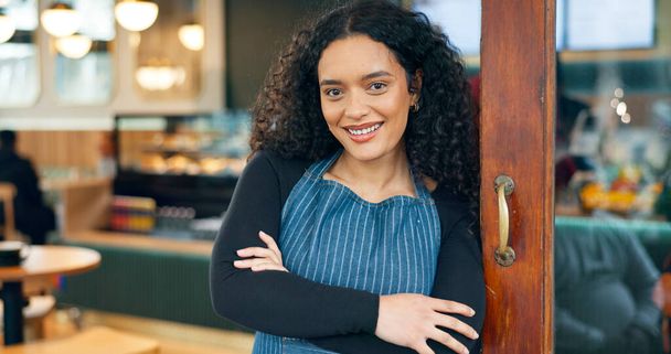 Small business, cafe and arms crossed with smile, waitress and startup for coffee shop, door and restaurant. Portrait, woman and entrance for retail, proud and confident at store, happiness and open. - Foto, afbeelding