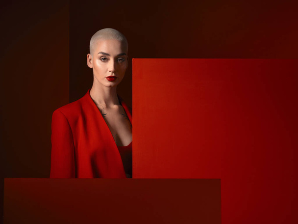 Portrait, fashion and serious woman in red suit in studio isolated on a background mockup space. Face, makeup and model with cosmetics, aesthetic or stylish, trendy or classy clothes from Switzerland. - Foto, Imagem