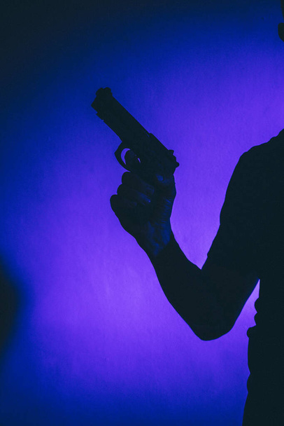 Zabójca strzelec trzyma pistolet artystyczny okładka książki fotograficznej projekt z kolorami i oświetleniem. - Zdjęcie, obraz