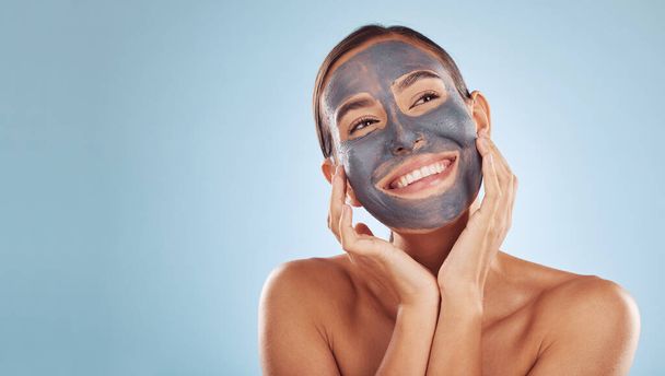Woman, face mask and thinking of charcoal skincare, natural beauty and cosmetics benefits on studio, blue background. Ideas of person or model for facial collagen, skin care and dermatology on banner. - Photo, Image