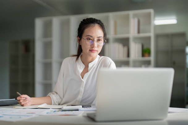 Portrait der schönen jungen Geschäftsfrau asiatischen sitzt im Büro modernen Arbeitsplatz und tippt auf Laptop. - Foto, Bild