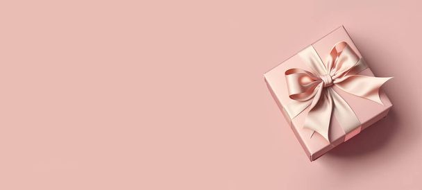 Pink gift box with satin bow on pink background. Banner, top view, space for text. - Photo, Image