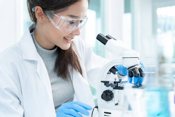 A tudós biokémiai mintákat analizál fejlett tudományos laboratóriumban. Orvosi professzionális használat mikroszkóp néz mikrobiológiai fejlődési vírus. Biotechnológiai kutatás a tudományos laborban. - Fotó, kép