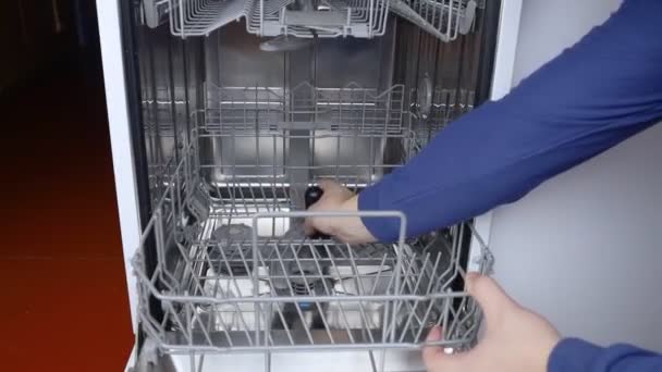 Dishwasher repair. A service center representative diagnoses and repairs a dishwashing machine at home. Specialist in working with home appliances. Call a technician to your home. Close-up - Footage, Video