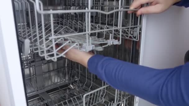 Dishwasher repair. A service center representative diagnoses and repairs a dishwashing machine at home. Specialist in working with home appliances. Call a technician to your home. Close-up - Footage, Video