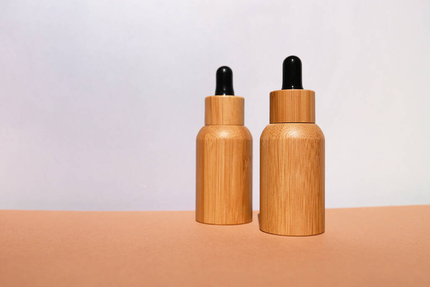 Бамбукові крапельні пляшки з косметичною рідиною на світлому фоні. - Фото, зображення