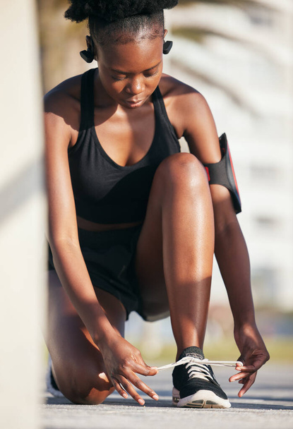 Donna nera, scarpe outdoor e cravatta per allenamento, allenamento ed esercizio. Sport, fitness e atleta africano allacciano lacci sulle scarpe da ginnastica per iniziare a correre, prepararsi per cardio e jogging, salute e benessere. - Foto, immagini
