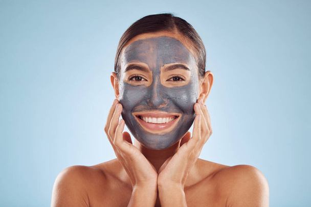 Woman, charcoal and face mask for skincare, beauty and natural cosmetics cleaning product on studio, blue background. Portrait of person or model in facial collagen and mud skin care for dermatology. - Photo, Image