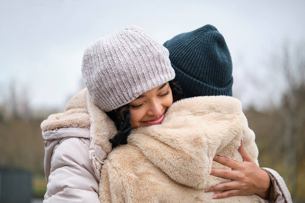 Dominicana casal lésbico abraçando com carinho e amor na rua em um dia de inverno. - Foto, Imagem