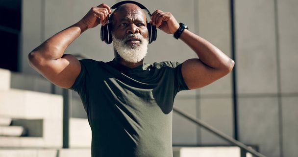 Fitness, music headphones and black man on stairs in city, workout and exercise for body health. Radio, steps and senior athlete in urban town, listening to audio sound and serious, thinking or relax. - Photo, Image