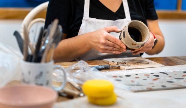 Prace ceramiczne. Zbliżenie rąk kobiety w średnim wieku pracujących z gliną - Zdjęcie, obraz