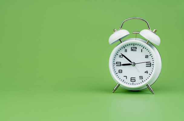 Білий будильник показує час роботи з часовою важливістю пунктуальності Білий годинник на зеленому тлі - Фото, зображення