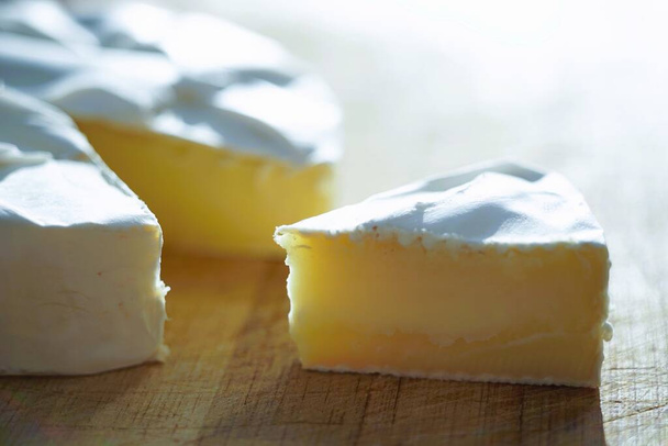 Rebanada de queso Camembert y entero en una mesa de madera
. - Foto, imagen