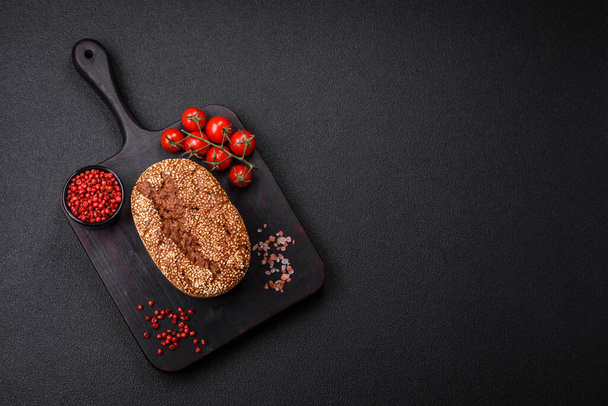 Вкусный свежий хрустящий коричневый хлеб с семенами и злаками на темном бетонном фоне - Фото, изображение